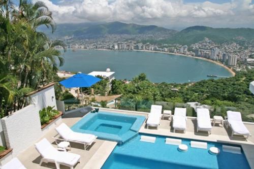 a swimming pool with chairs and a view of a city at Acapulco Villa Brisas 26 in Acapulco