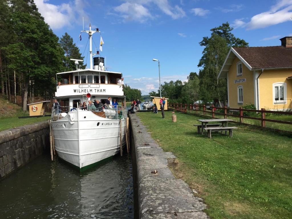 a white boat is docked in a canal at Brådtom Slusscafé & Stugor in Norrköping