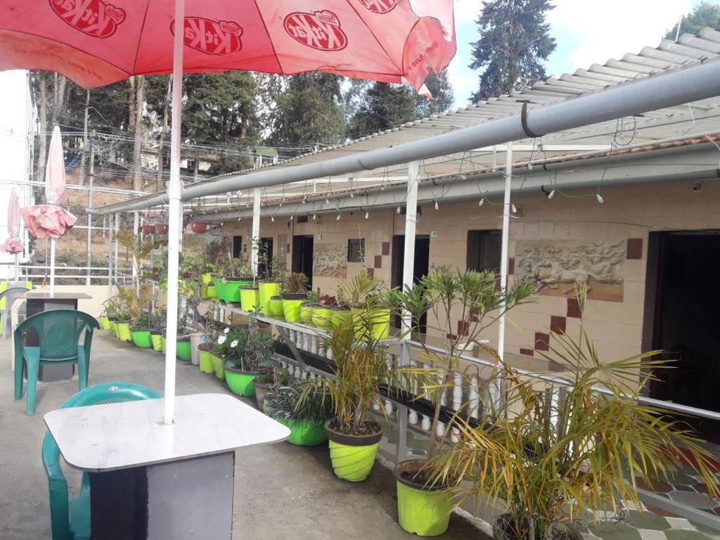 a patio with a table and chairs and an umbrella at Hill Inn Rooms an HomeStay in Ooty