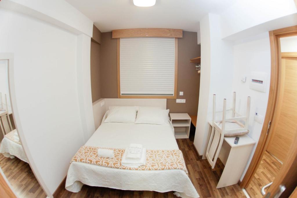 a small bedroom with a bed and a window at Pension Esquina in Melide