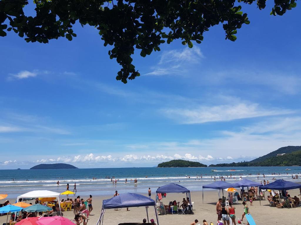 un groupe de personnes sur une plage avec parasols dans l'établissement Condomínio Ville II, à Ubatuba