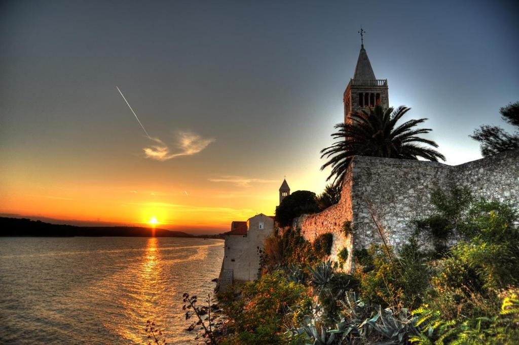 un tramonto sull'acqua con un castello e una chiesa di Paradise apartment - Old town Rab a Rab