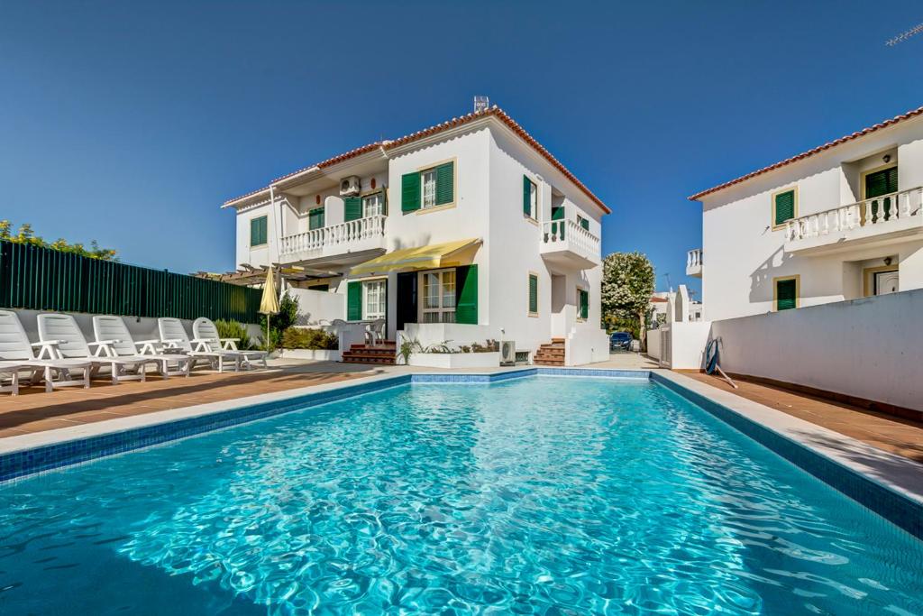 a villa with a swimming pool in front of a house at Bougainvilleas Villa - Private Pool and Parking, Nearby Beach in Altura
