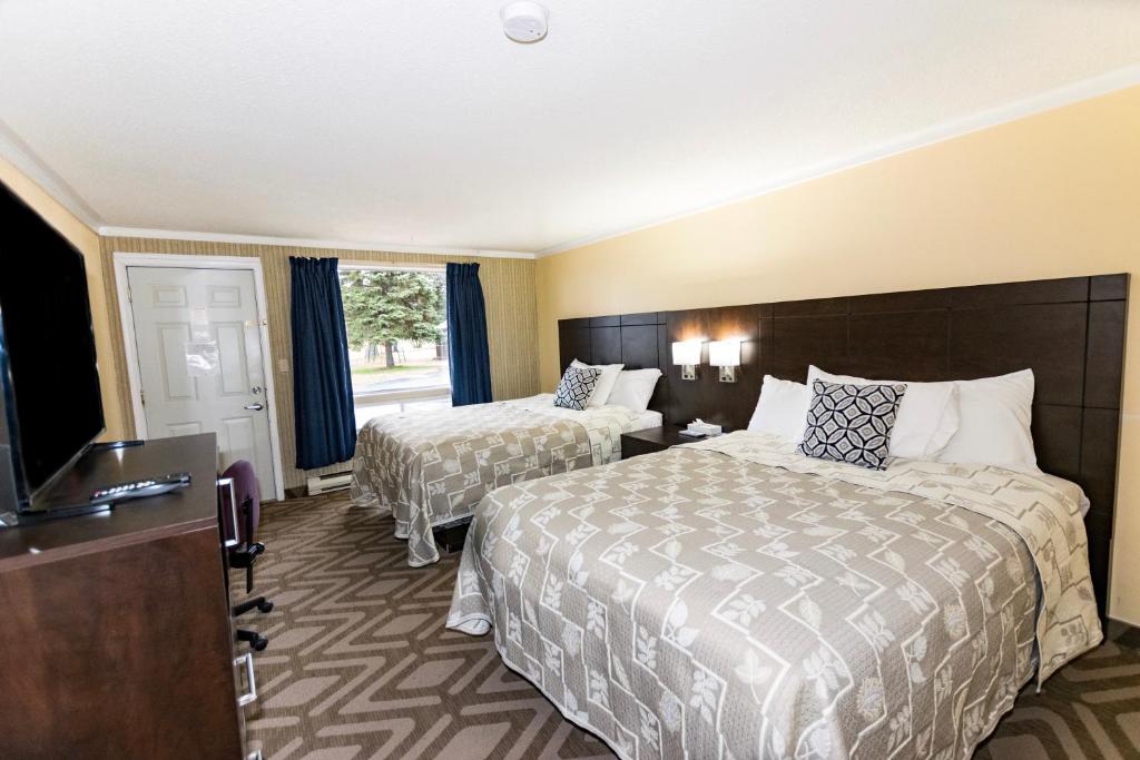 um quarto de hotel com duas camas e uma televisão de ecrã plano em Countryside Inn em Kingston