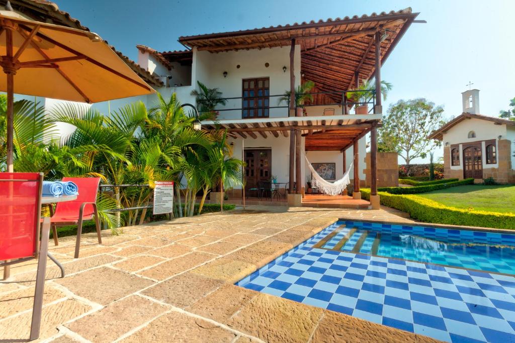 a house with a swimming pool and an umbrella at Casa Bari La Antigua in Barichara