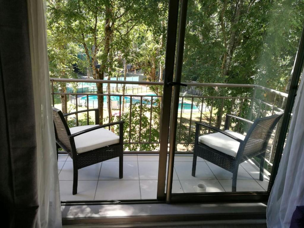 un balcon avec deux chaises et une vue sur une piscine dans l'établissement Departamento Parque Suizo Pucon, à Pucón