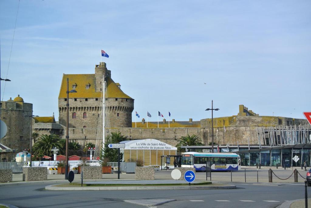 un autobús está estacionado frente a un castillo en Au Logis De La Rance Bed and Breakfast, en Saint-Jouan-des-Guérets
