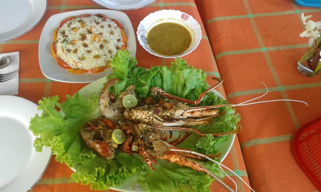 un piatto di cibo con un'aragosta e insalata su un tavolo di SunRay Rest - Beach View Homestay a Mirissa