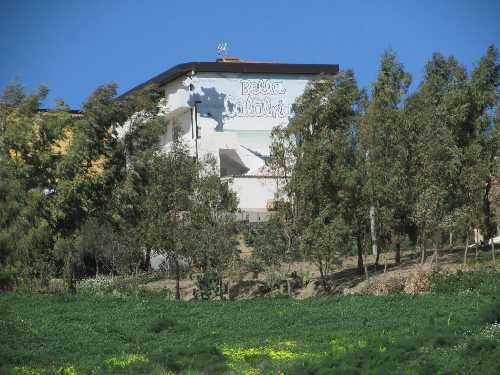 un bâtiment au sommet d'une colline plantée d'arbres dans l'établissement Ostello Bella Calabria, à Torre Ritani