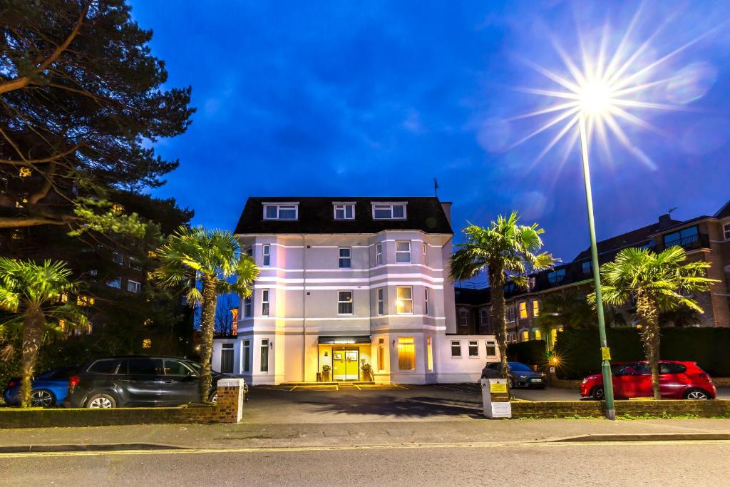 uma grande casa branca com palmeiras e uma luz de rua em Connaught Lodge em Bournemouth