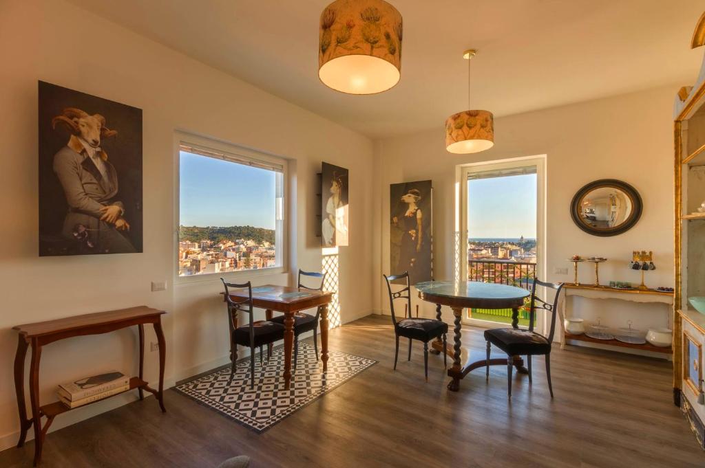 a living room with a table and chairs and two windows at Eleventh Floor Suites in Cagliari