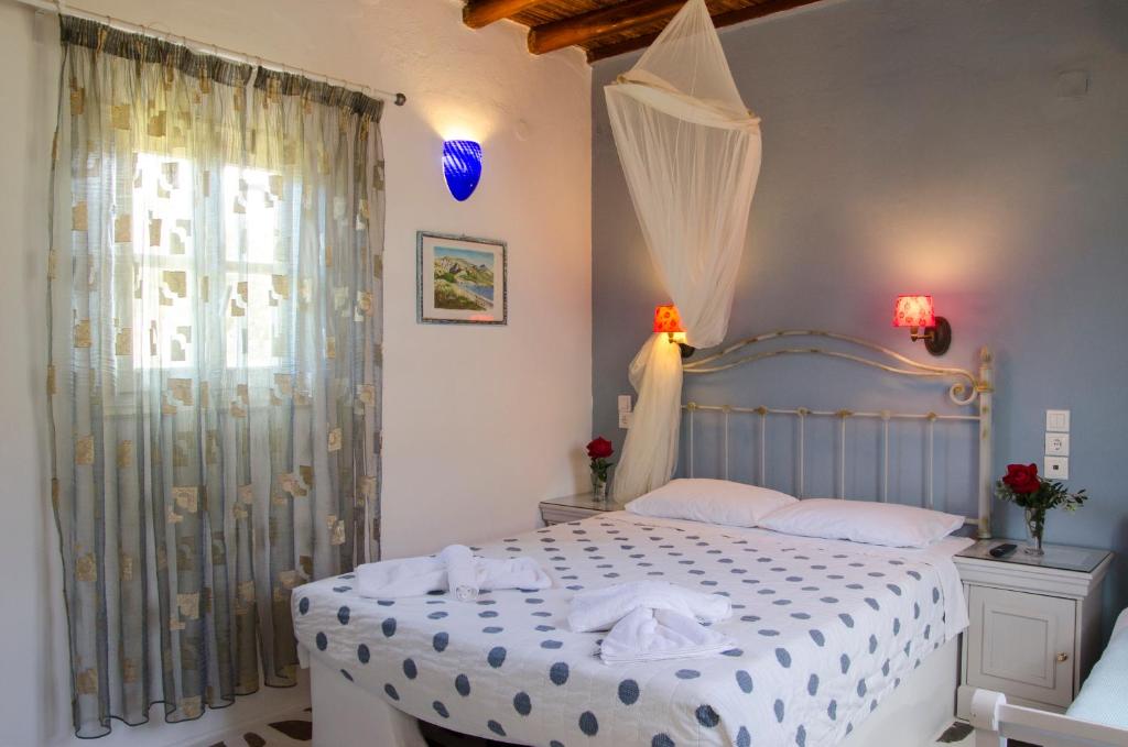 a bedroom with a white bed and a window at Lakki Village in Aegiali