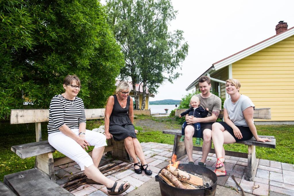 a group of people sitting around a fire pit at Nivagården in Korpikylä