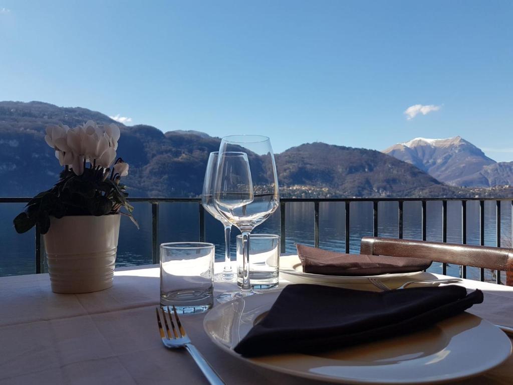 een tafel met een bord en wijnglas op een balkon bij Foresteria Lombarda La Spiaggia in Lierna