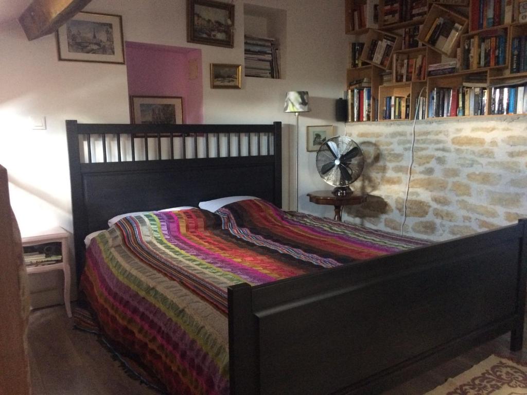 a bedroom with a bed with a colorful blanket on it at Gîte Chambre de la Tante Camille - Les Filles Tresy in Passenans