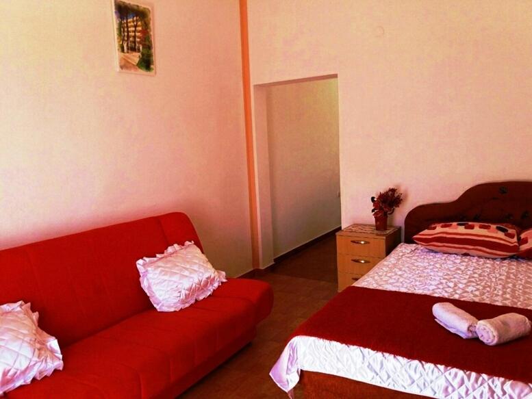 a living room with a red couch and a bed at Apartments Sun Igalo Montenegro in Igalo