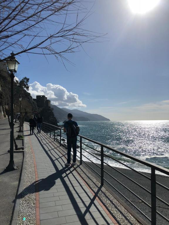 Ein Mann steht neben einem Zaun am Wasser. in der Unterkunft Appartamento via Roma 56 in Monterosso al Mare