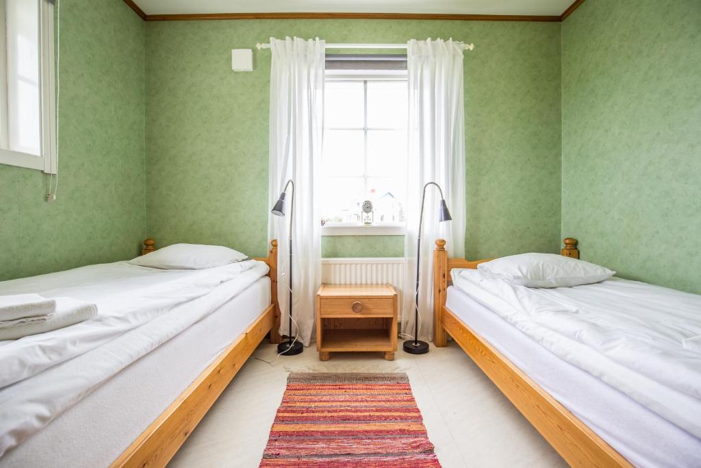 two beds in a room with green walls and a window at Nivagården in Korpikylä