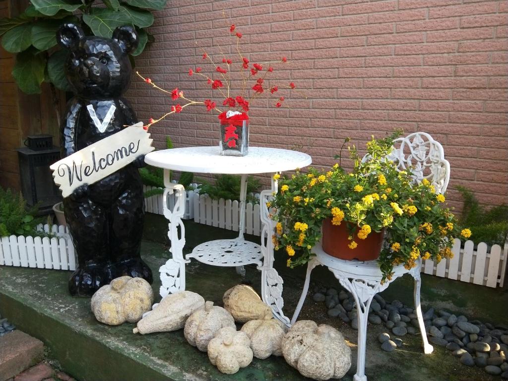 a table and chairs with flowers and a bear statue at Taichung Xinshe Garden Life Homestay B&amp;B in Xinshe