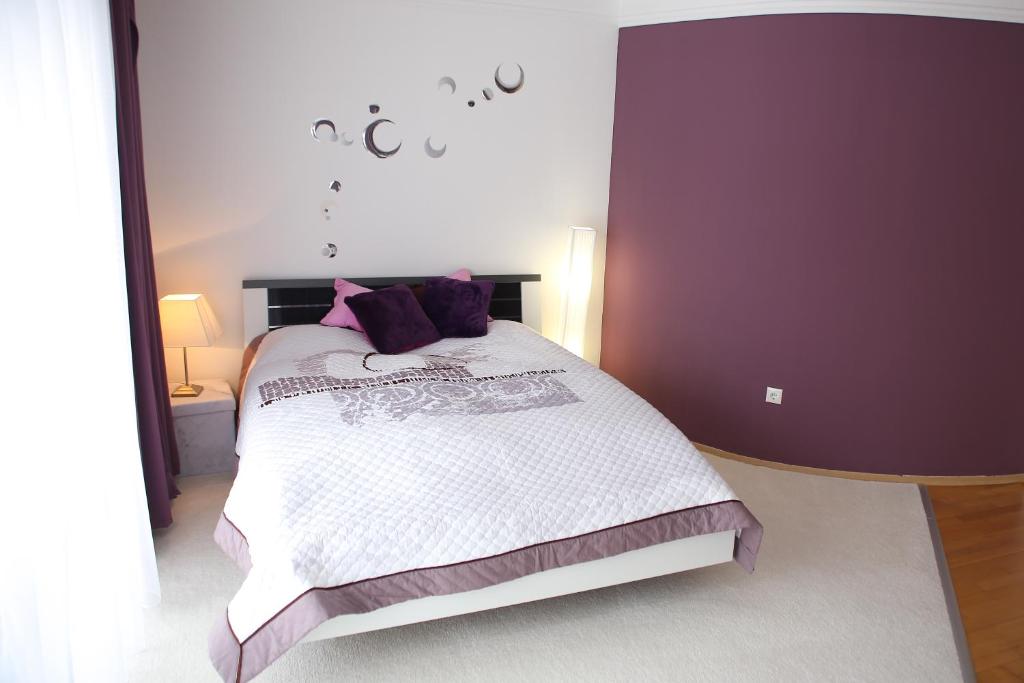 ヘーヴィーズにあるLila Apartmanのベッドルーム1室(紫色の枕が付いたベッド1台付)