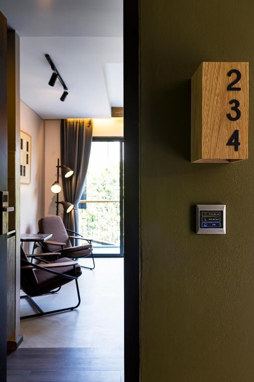 A glimpse into a bright guest room with a lounge chair, floor lamp and tall window.