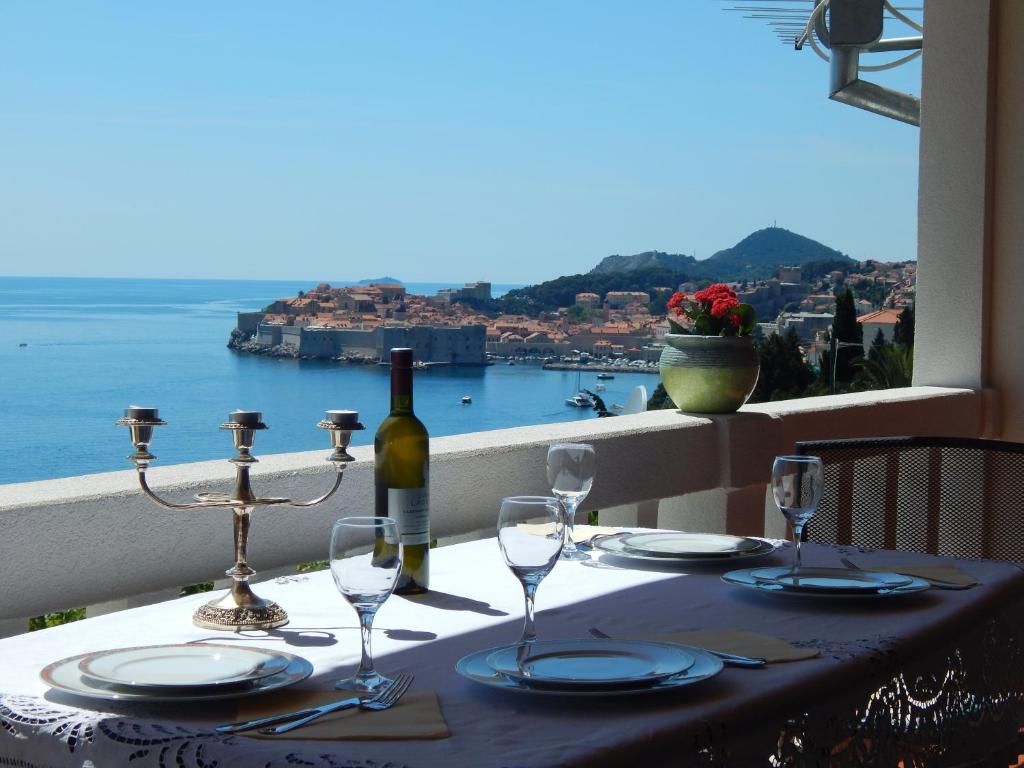 a table with a bottle of wine and glasses on a balcony at Apartment Perica in Dubrovnik