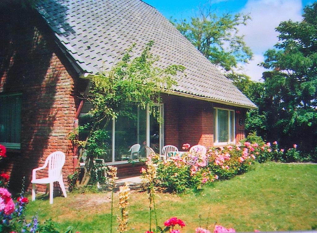 een huis met stoelen en bloemen in de tuin bij Haus Ebeling in Norderney