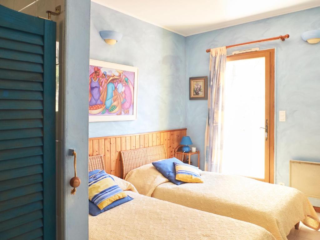 2 letti in una camera con pareti blu e finestra di Les Bergeries a Tourrettes-sur-Loup