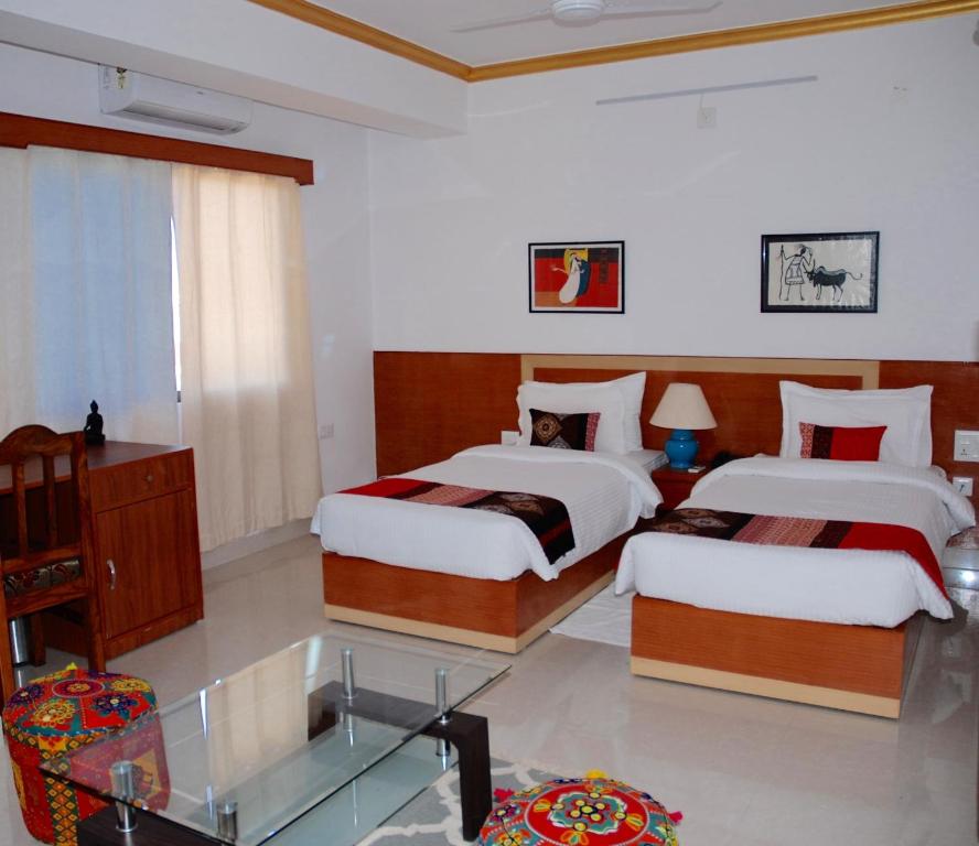 a bedroom with two beds and a glass table at The Bodhgaya Hotel School in Bodh Gaya