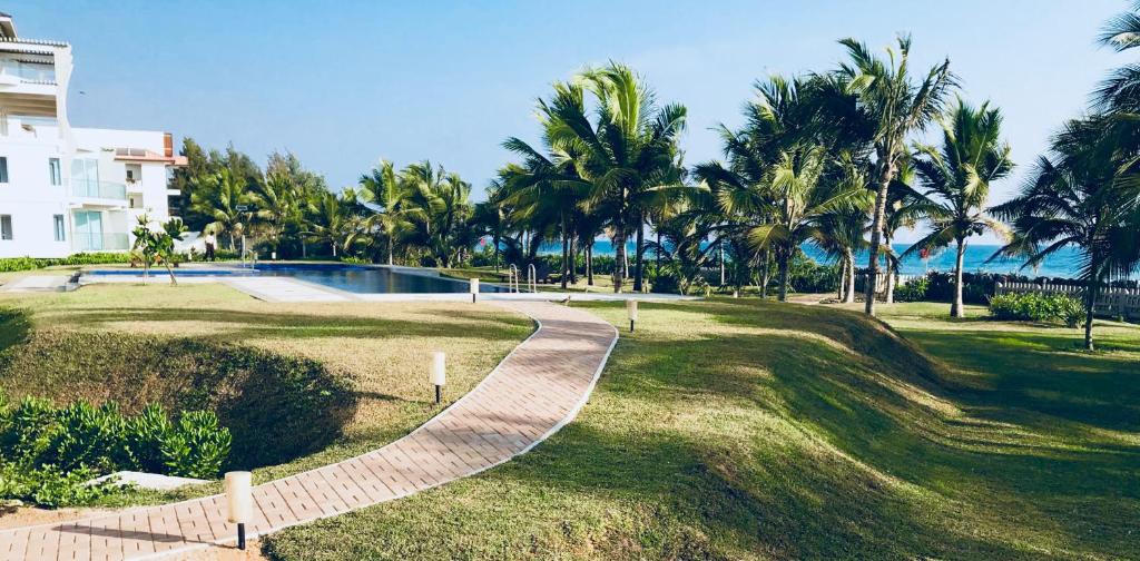 un complexe avec une piscine et des palmiers dans l'établissement Nilaveli Ocean Condos, à Trincomalee