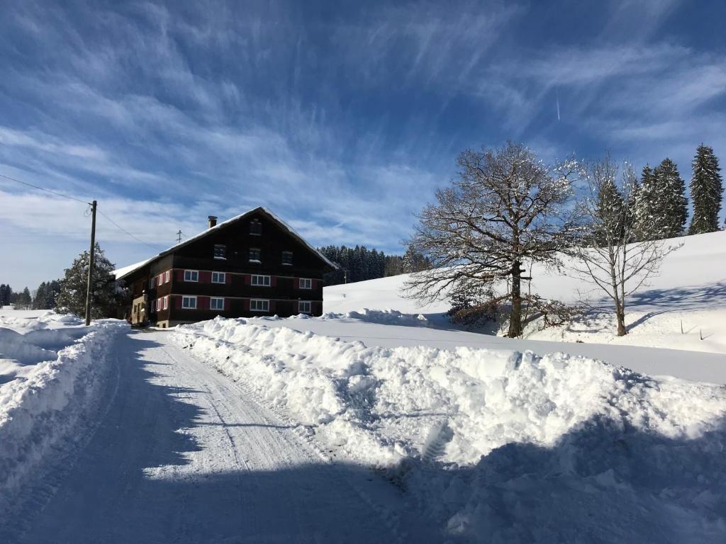 a snow covered road in front of a house at Bergstätt Lodge in Immenstadt im Allgäu