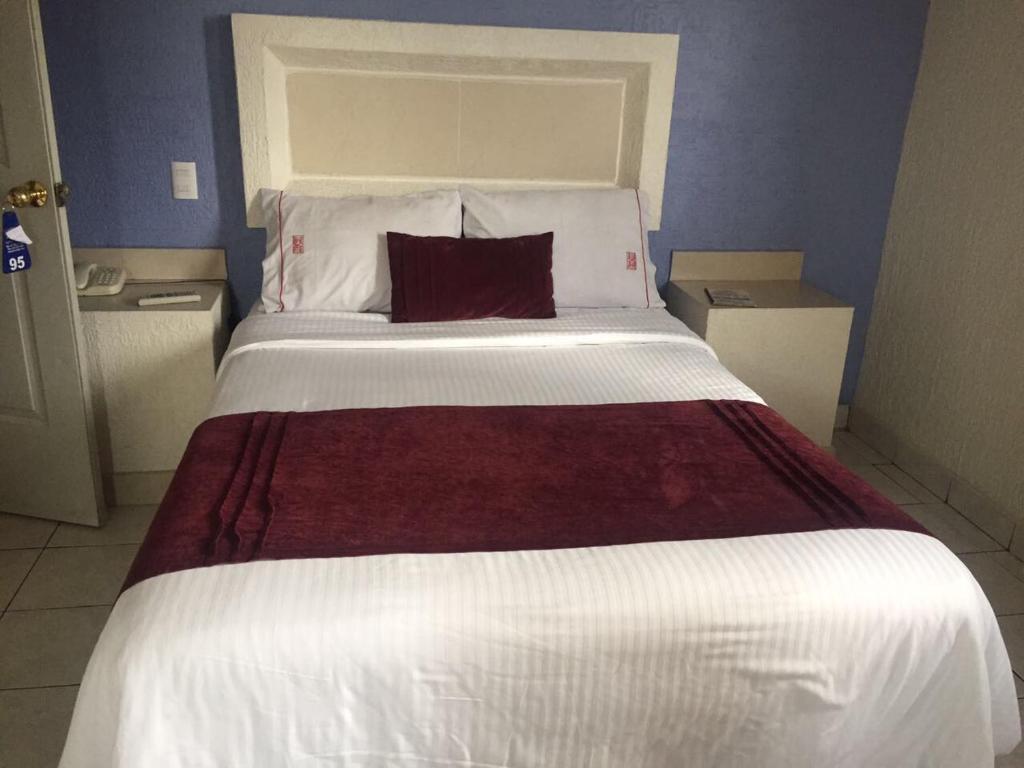 un grande letto bianco con un cuscino rosso di Hotel La Paz a Guadalajara