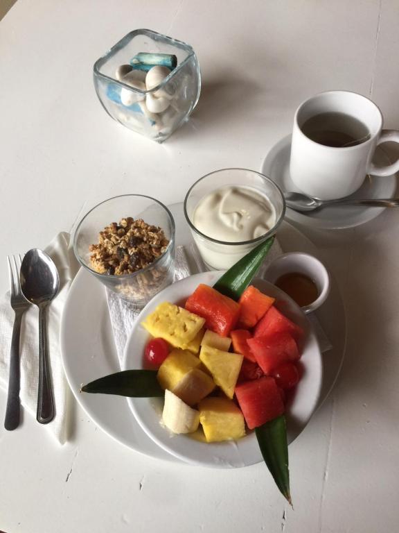 a plate of fruit on a table with a cup of coffee at Hotel Bocas del Toro in Bocas del Toro