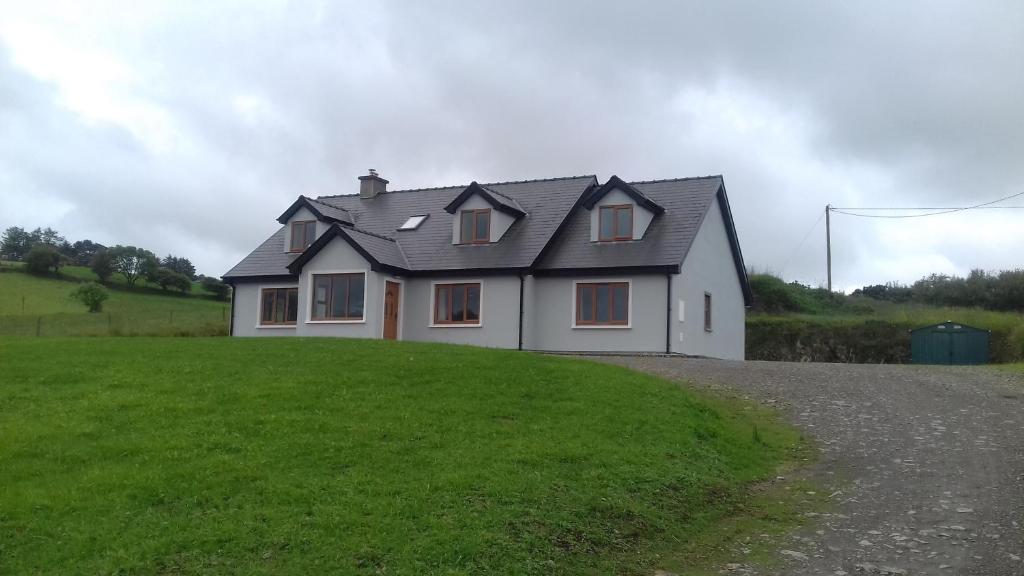 a house on top of a grassy hill at Orchard lodge Bantry in Glanbannoo Upper