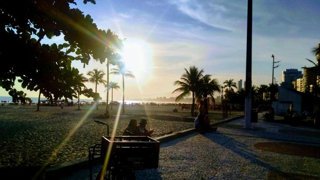 eine Gruppe von Menschen, die am Strand mit dem Sonnenuntergang sitzen in der Unterkunft Casa do Ph in Praia Grande