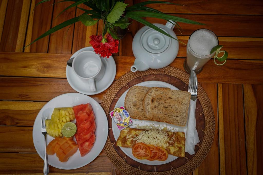 a table with a plate of food with toast and fruit at Martas Hotel in Gili Trawangan