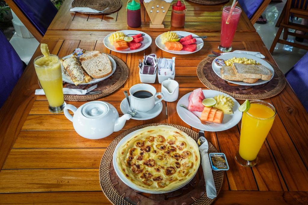 a wooden table topped with plates of breakfast food at Martas Hotel in Gili Trawangan