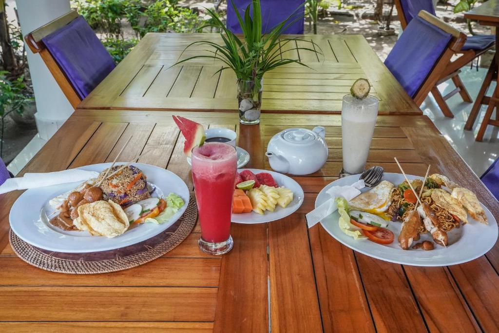 a table with two plates of food and a drink at Martas Hotel in Gili Trawangan