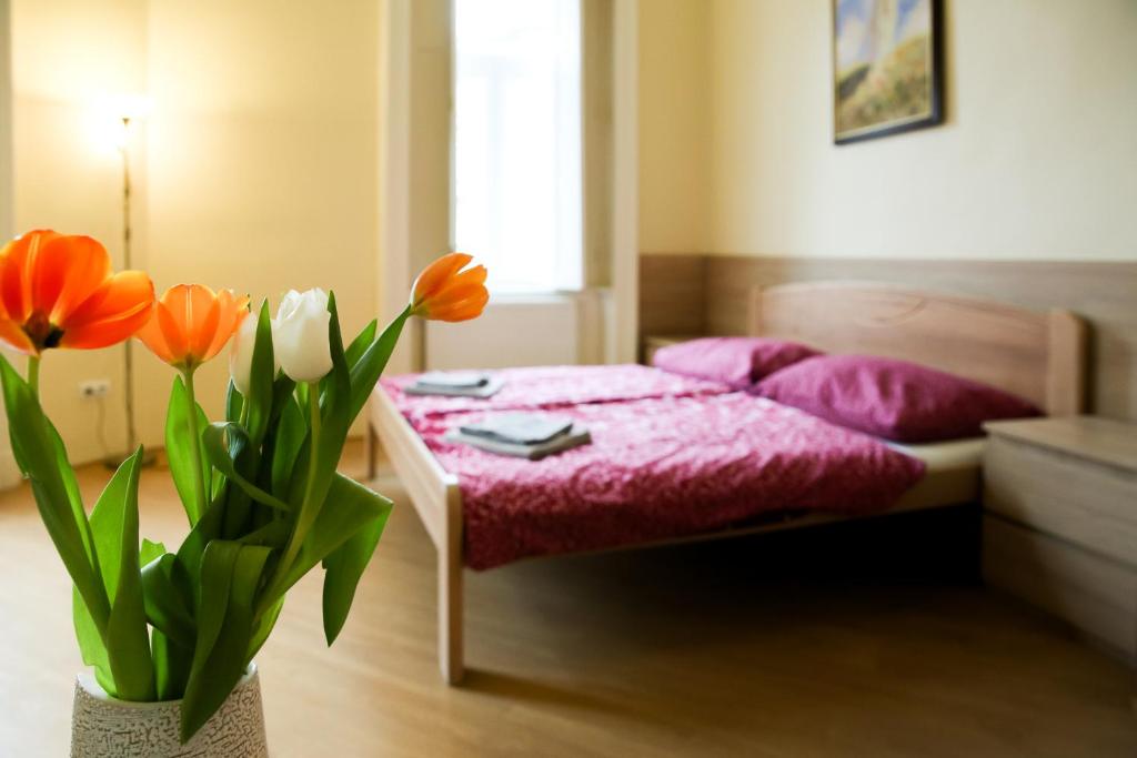 a bedroom with a bed with red sheets and orange flowers at East Private Rooms in Budapest