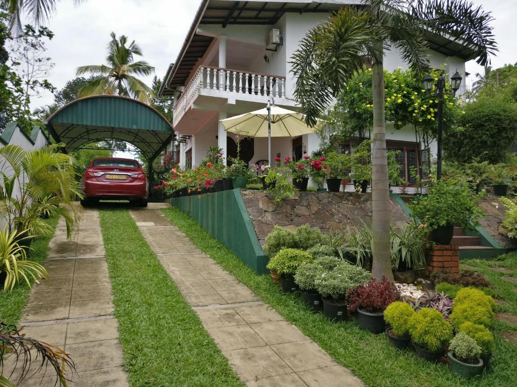 a car parked in front of a house with plants at Samanala Garden Holiday Home in Hikkaduwa