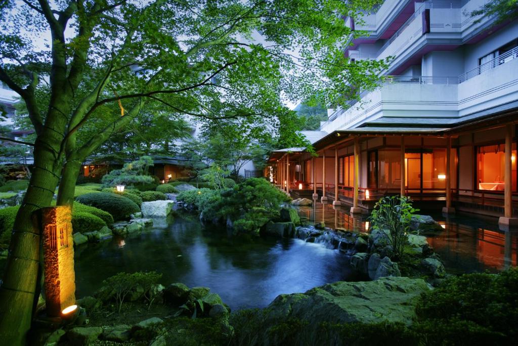 a garden with a pond in front of a building at Kinugawa Grand Hotel Yumenotoki in Nikko