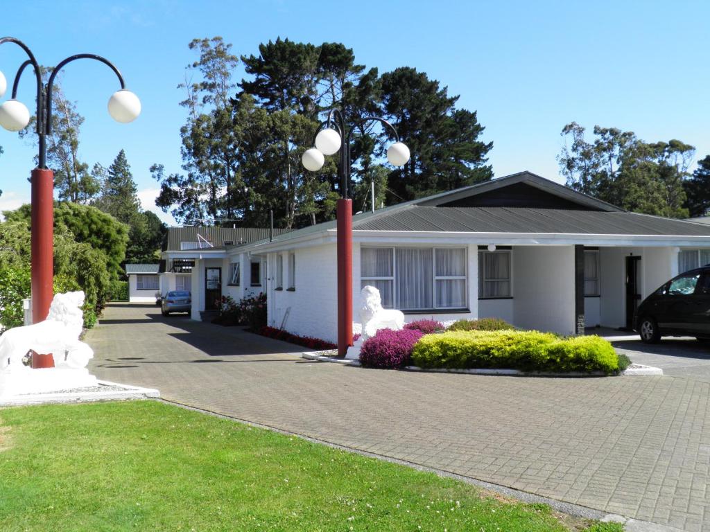 a house with two white statues in front of it at Queens Park Motels in Invercargill