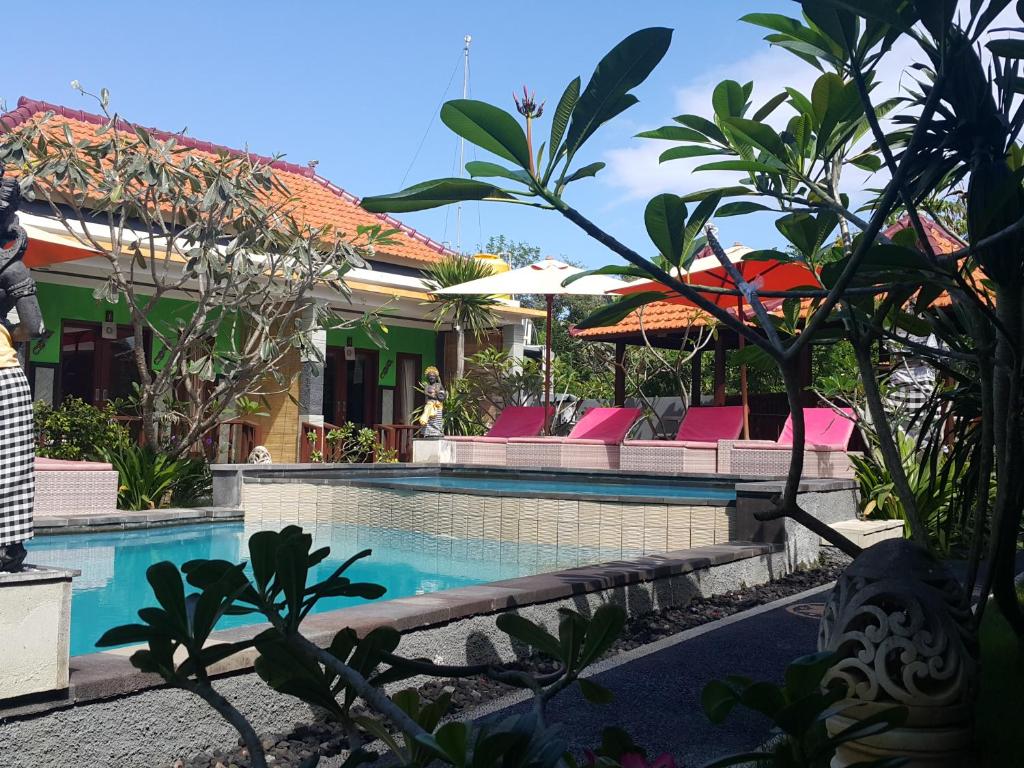 a pool at a resort with chairs and umbrellas at The Taran Villas Lembongan in Nusa Lembongan