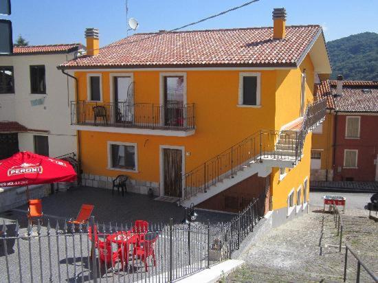 ein gelbes Haus mit Tischen und Stühlen davor in der Unterkunft B & B IL TRATTURO in San Pietro Avellana