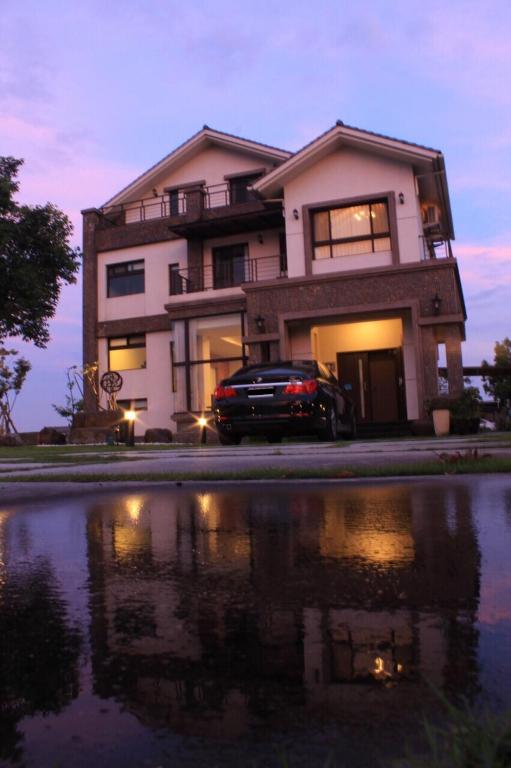 a house with a car parked in front of a pond at CarNo B&amp;B in Yuanshan