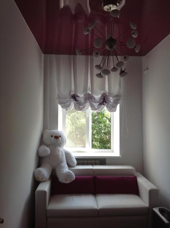 um urso de peluche sentado num sofá em frente a uma janela em Central Point Apartment em Lviv