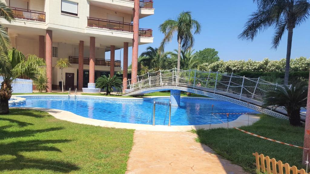 a bridge over a swimming pool in front of a building at SALINAS GANDIA - Solo alquiler Familias in Gandía