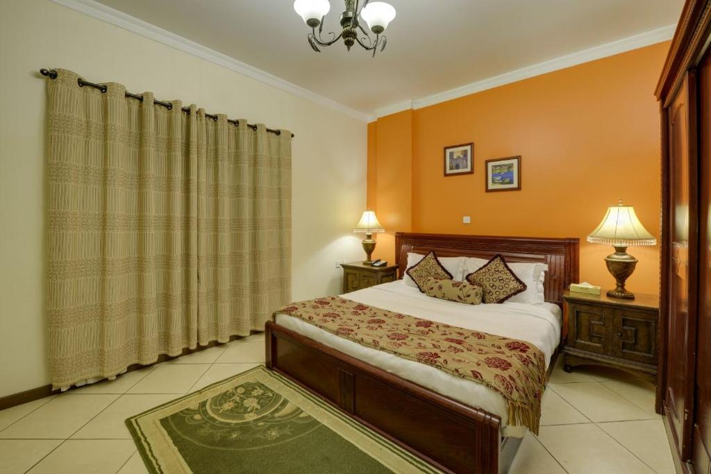 1 dormitorio con 1 cama, 2 mesas y 2 lámparas en Ramee Suite Apartment 4, en Manama