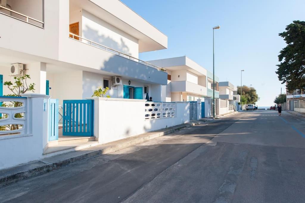 an empty street next to a building with a blue fence at Guest House Matteo in Torre Lapillo