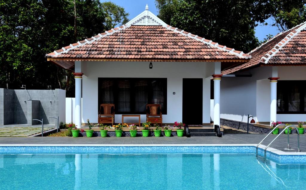 a house with a swimming pool in front of a house at Marari Green Villas in Mararikulam
